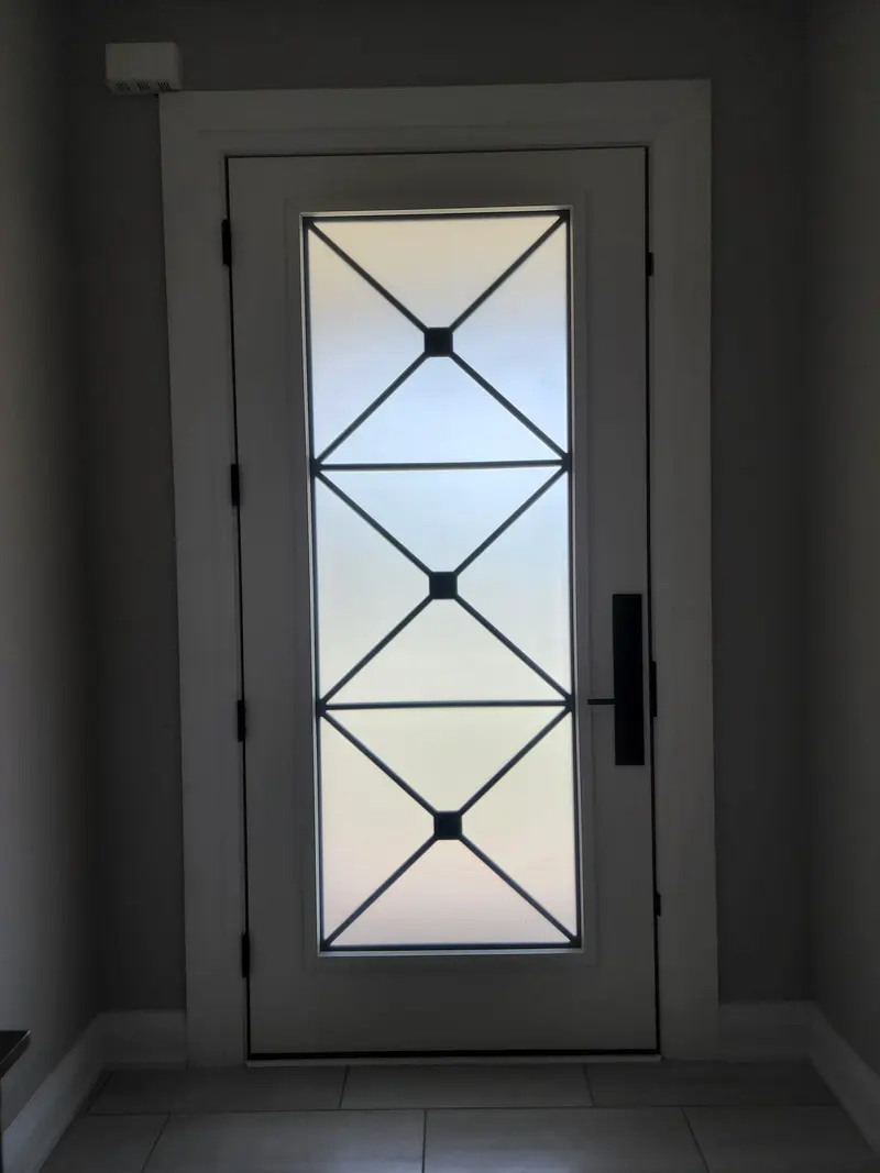 Black entry door with wrought-iron glass insert