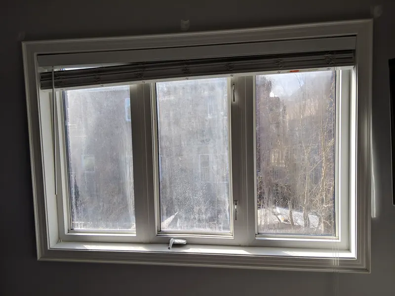 Before: white three-panel casement window with heavy fog between the panes