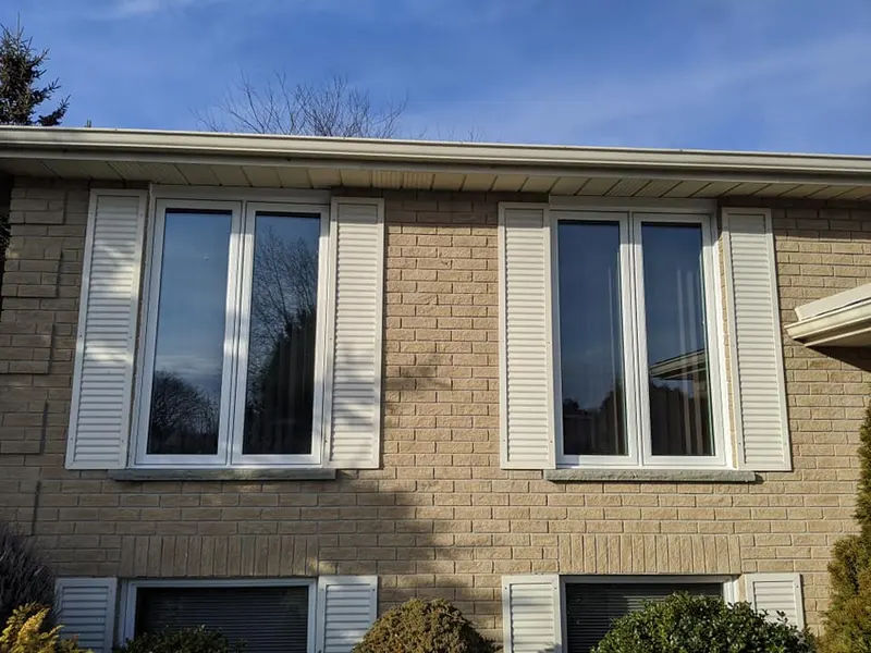 White vinyl windows with shutters on a brick home